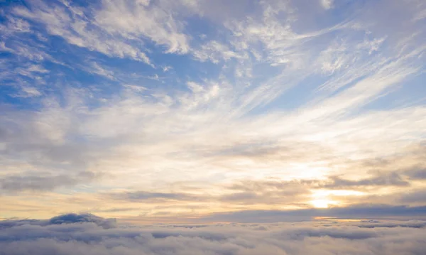 Aerial view gold sunrise over clouds in blue sky. Aerial top view cloudscape. Texture of clouds. View from above. Orange sunrise or sunset over clouds. Panorama clouds texture