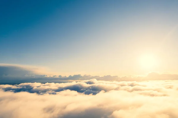 Aerial view gold sunrise over clouds in blue sky. Aerial top view cloudscape. Texture of clouds. View from above. Orange sunrise or sunset over clouds. Panorama clouds texture