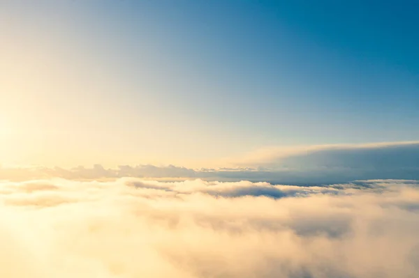 Aerial view gold sunrise over clouds in blue sky. Aerial top view cloudscape. Texture of clouds. View from above. Orange sunrise or sunset over clouds. Panorama clouds texture