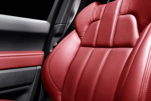 Modern luxury car red leather interior. Part of red leather car seat details with stitching. Interior of prestige car. Comfortable perforated leather seats. Perforated leather.