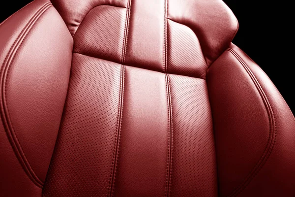 Modern luxury car red leather interior. Part of red leather car seat details with stitching. Interior of prestige car. Comfortable perforated leather seats. Perforated leather.