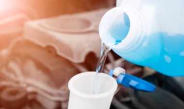 Plastik kutudan araba yıkama sıvısı deposuna sıvı dökülüyor. Ön cam su tankını çamaşır suyuyla kapat..