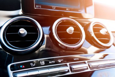 Lüks modern arabanın havalandırma güvertesi. Modern siyah deri iç döşeme. Doğal ahşap panel. Siyah deri delinmiş. Arabanın içi. Arabanın içinde güneş ışınları var.