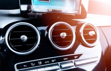 Lüks modern arabanın havalandırma güvertesi. Modern siyah deri iç döşeme. Doğal ahşap panel. Siyah deri delinmiş. Arabanın içi. Arabanın içinde güneş ışınları var.