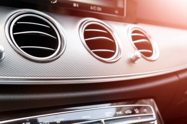 Lüks modern arabanın havalandırma güvertesi. Modern siyah deri iç döşeme. Doğal ahşap panel. Siyah deri delinmiş. Arabanın içi. Arabanın içinde güneş ışınları var.