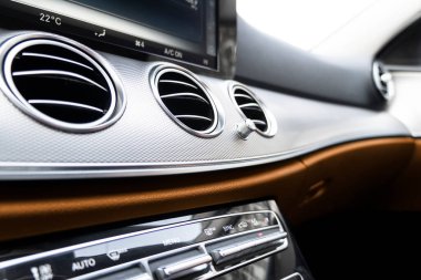 Kahverengi lüks modern araba. Direksiyon, vites kolu ve gösterge paneli. Modern araba iç dekorasyonunun ayrıntıları. Otomatik vites kolu. Pahalı arabada dikilmiş turuncu deri koltuklar.