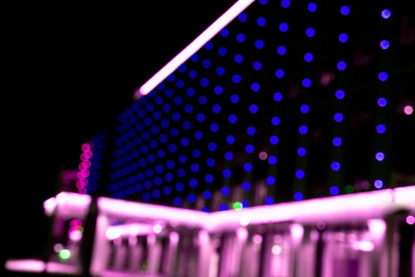 Blurred office building with illuminated facade exterior at night. Blurry modern business building  with bokeh light and defocused dots. Blur windows office building for background