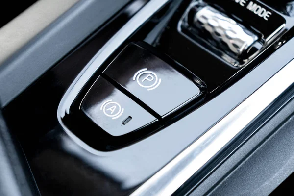 Detail of a parking brake in a modern car. Electronic parking brake button in a modern car. Button closeup.