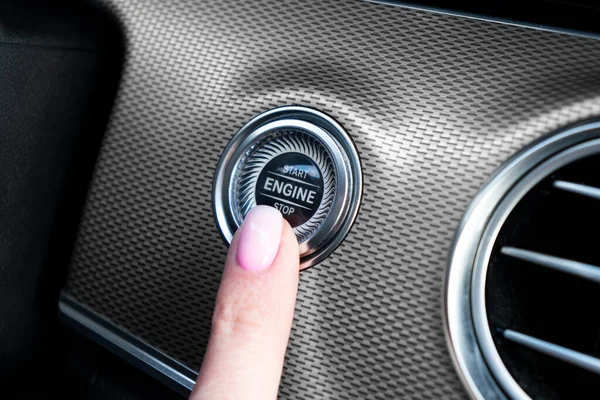 Car driver starting the engine with start stop engine button. Finger press engine start and stop button.  Modern car interior details. Hand finger press button in car