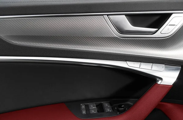 Car door handle inside the luxury modern car with red leather texture with stitching. Switch button control. Modern car interior details. Red perforated leather