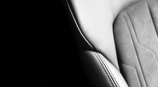 Modern luxury car black leather with alcantara interior. Part of black leather car seat details with white stitching. Interior of prestige car. Perforated leather seats isolated. Perforated leather.