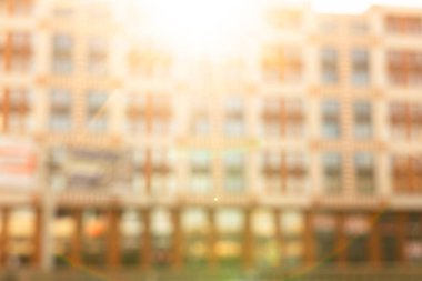 Gün batımında dış görünüşü aydınlanmış, soyut, bulanık bina. Bokeh ışığıyla bulanık modern bina ve güneş ışınlarıyla çözünmüş noktalar. Arkaplan için bulanık pencereler