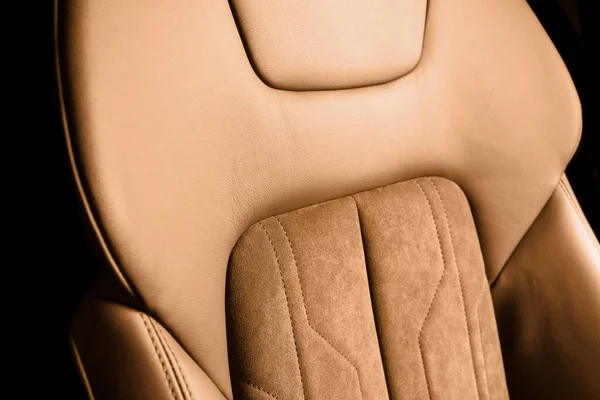 Modern luxury car brown leather with alcantara interior. Part of orange leather car seat details with white stitching. Interior of prestige car. Perforated leather seats isolated. Perforated leather.