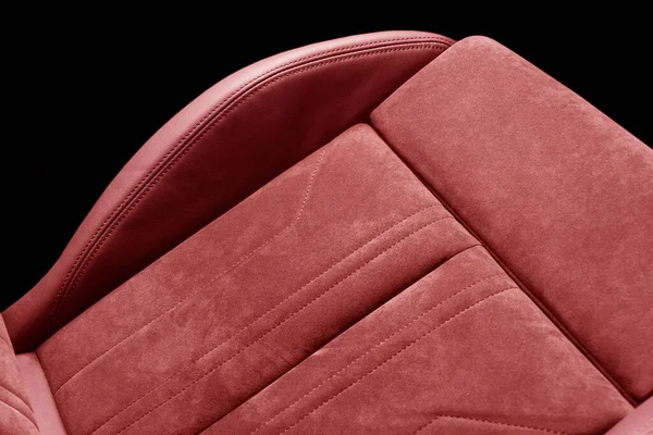 Modern luxury car red leather and alcantara interior. Part of red perforated leather car seat details with white stitching. Interior of prestige car. Comfortable perforated leather seats.