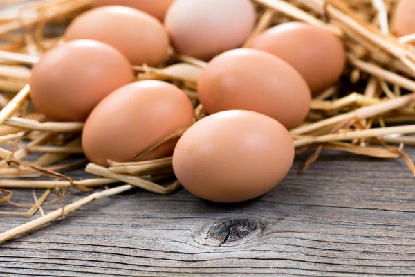 Свежие органические яйца на деревенской деревянной доске и соломе — стоковое фото