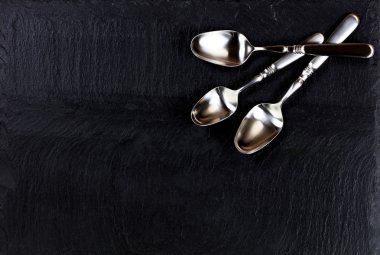Rustic spoons on slate stone background  clipart