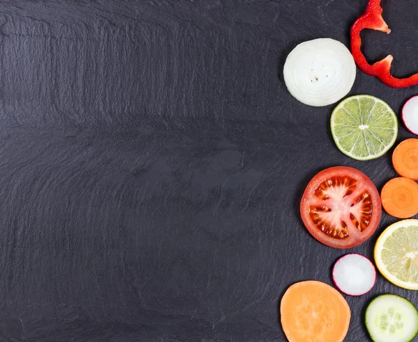 Frisches geschnittenes Gemüse und Obst auf Naturschieferboden — Stockfoto