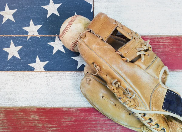 Old worn baseball mitt and ball on faded boards painted in Ameri — Stock Photo, Image