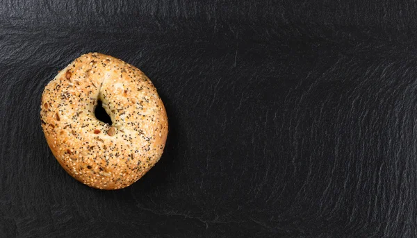 Grande bagel de semente no fundo de ardósia natural — Fotografia de Stock