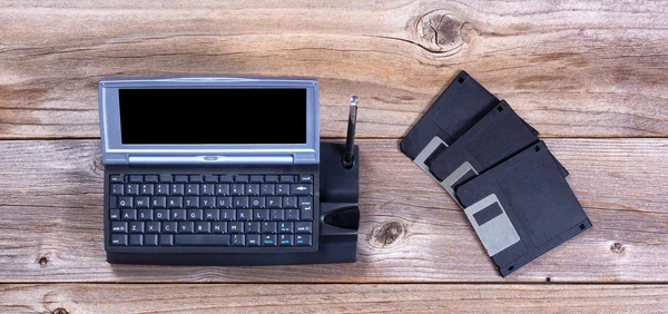 Vintage handheld computer en gegevens schijven op rustieke houten planken — Stockfoto