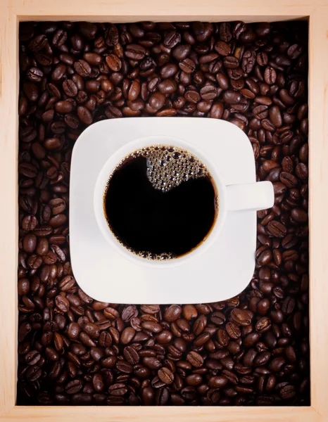 Fresh cup of dark coffee in box with roasted beans — Stock Photo, Image