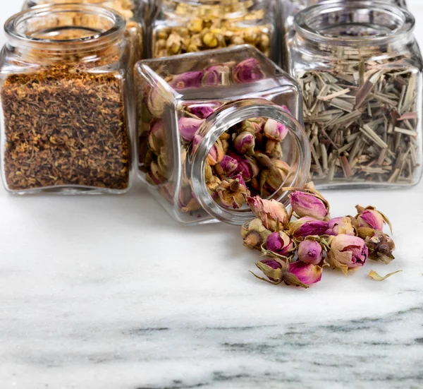 Spices and herbs in small glass jars pouring onto white marble s — Stock Photo, Image