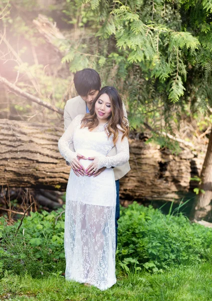 Esperando mãe e pai segurando uns aos outros ao ar livre com árvores e — Fotografia de Stock