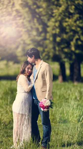 Expecting mom and dad in grassy field on bright day — Stock Photo, Image