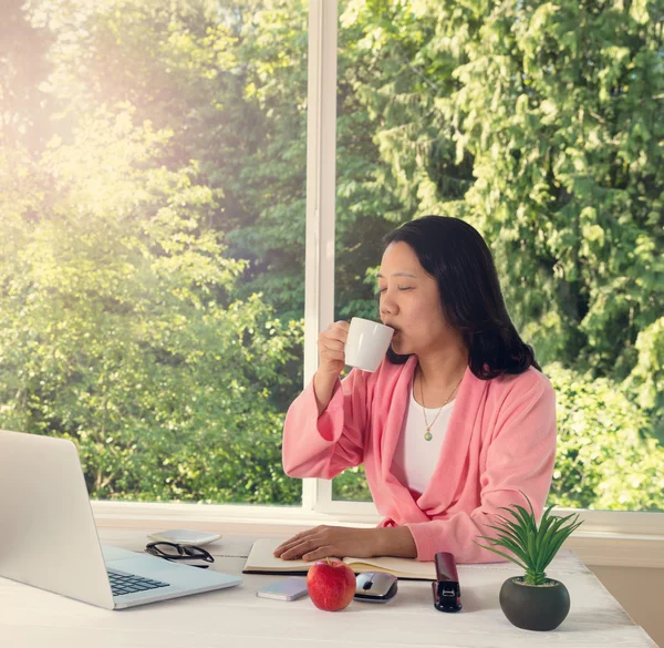 Mujer disfrutando de su café en la luz de la mañana mientras trabaja fro —  Fotos de Stock