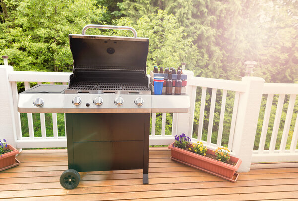 Bright daylight on deck wiht open barbecue cooker and bottled be