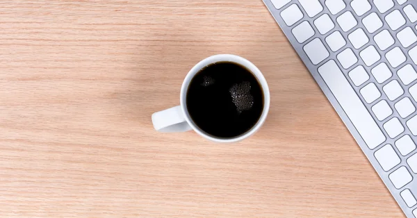 黑咖啡与键盘上红橡木桌面背景 — 图库照片