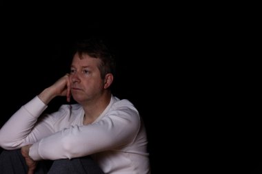 Depresif olgun adam koyu arka planda düşünme 