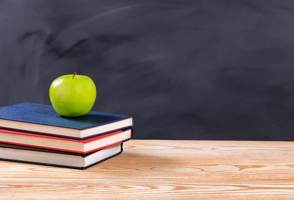 Tillbaka till skolböcker och grönt äpple framför raderas svart ch — Stockfoto