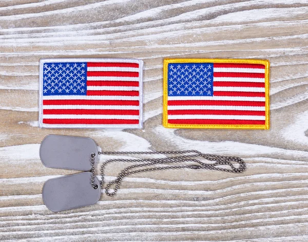 Small USA flag patches and military ID tags on rustic white wood — Stock Photo, Image