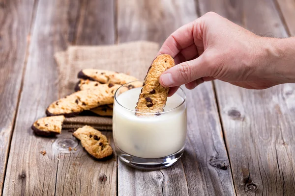 Hand dipping homemade chocolate chip cookies into full glass of — Stock Photo, Image