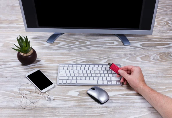 Hand som håller tummen enhet med office datorinstallation i backg — Stockfoto