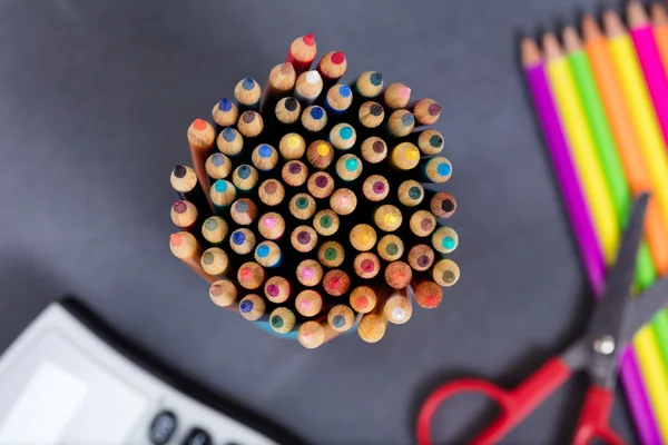 Colorful pencil tips with student supplies and erased chalkboard — Stock Photo, Image
