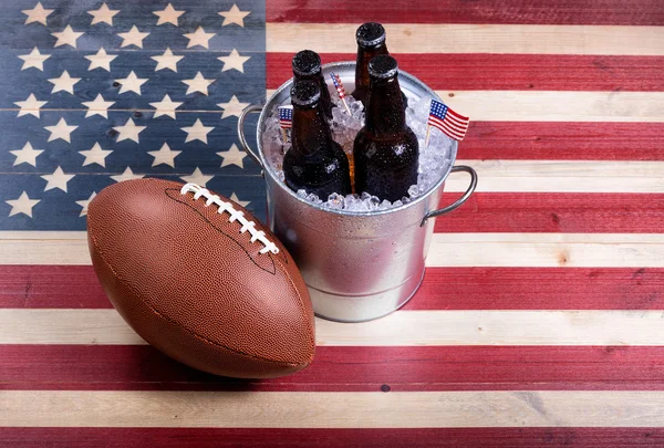 Fútbol americano y cerveza helada en madera rústica bandera de EE.UU. —  Fotos de Stock