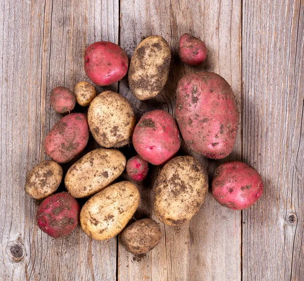 Pommes de terre crues non nettoyées sur des planches rustiques en bois — Photo