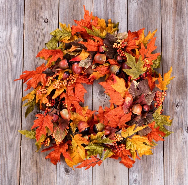 Kranz aus Herbstblättern und Eicheln auf rustikalen Holzbrettern — Stockfoto
