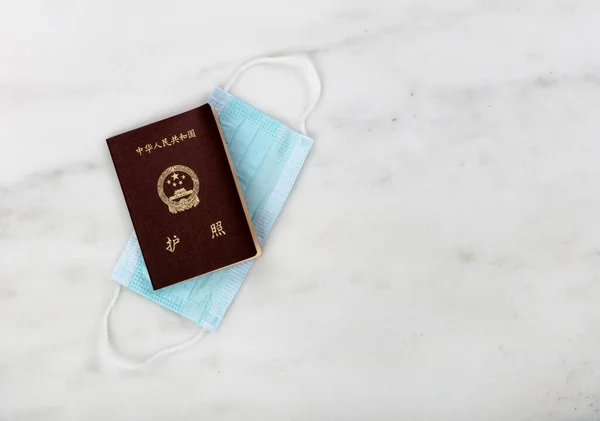 持中国护照和个人口罩在大脑皮层大流行期间旅行 — 图库照片