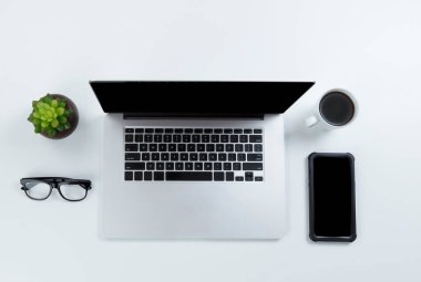 Laptop bilgisayarı, kahve ve akıllı telefonlu ofis masası. Düz yatay formatta kopyalama alanı olan başlık. 