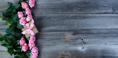 Açık pembe güller ve kırsal ahşap tahtalar üzerinde hediye kutusu. Anneler Günü konsepti düz konseptte.  