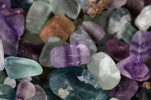 选择聚焦于框架中央的紫色剥光天然抛光玻璃石 其周围有多种颜色的石头 — 图库照片