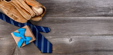 Babalar günü konsepti mavi kravat, beysbol eşyaları ve düz bir biçimde sade ahşap zemin üzerine bir hediye kutusu.