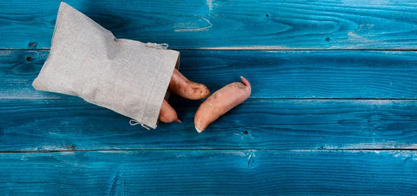 Burlap Bag Sweet Potatoes Spilling Out Blue Rustic Wooden Table — Stock Photo, Image