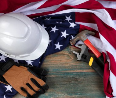 Amerikan bayrağı ve soluk mavi ahşap üzerine inşaat ekipmanlarıyla Mutlu İşçi Bayramı konsepti 