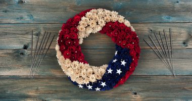 Wreath with United States national colors of red, white and blue with stars plus sparklers on faded blue wooden planks for happy memorial or Independence Day background concept  clipart