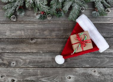 Karla kaplı Noel Baba şapkası her zaman yeşil dallar artı solmuş ahşap tahtalar üzerinde hediye kutusu Mutlu Noeller ya da mutlu noeller bayramı kutlaması konsepti 