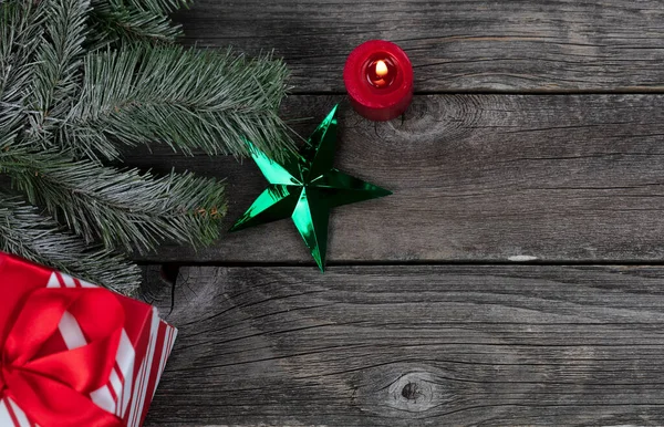 1つの緑の星の装飾と輝くキャンドル ギフトボックスと陽気なクリスマスや幸せな新年のお祝いのコンセプトのための素朴な木製の板の雪のモミの枝の装飾 — ストック写真